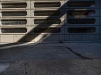 a black fire hydrant stands next to an apartment building that has large windows in the wall