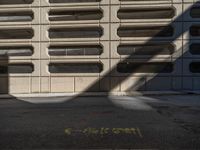 a black fire hydrant stands next to an apartment building that has large windows in the wall