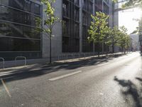 the street in front of a tall building on a sunny day with trees on both sides