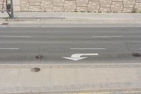 a white arrow painted on the side of a road in the middle of nowhere,