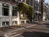 an empty sidewalk is shown in a city area, with brick pavements and parked motorcycles