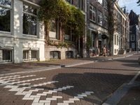 an empty sidewalk is shown in a city area, with brick pavements and parked motorcycles