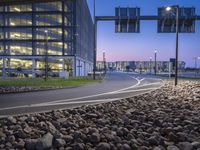 a paved road near a large building at dusk in an urban area at dusk,