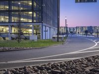 a paved road near a large building at dusk in an urban area at dusk,