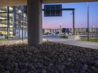 a paved road near a large building at dusk in an urban area at dusk,