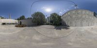 a view looking through a fisheye lens of the side of a building in a circle with a skateboarder performing a trick on a skate board