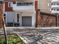 an empty brick sidewalk in front of a building with bikes parked next to it behind a fence