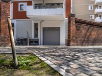 an empty brick sidewalk in front of a building with bikes parked next to it behind a fence