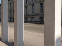 two people on motorcycles riding past pillars at an intersection in the city setting on a sunny day