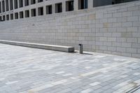 a stone wall sits in the middle of a brick walkway and sidewalk in front of a building with glass windows