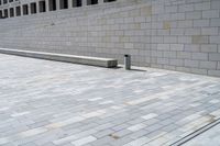 a stone wall sits in the middle of a brick walkway and sidewalk in front of a building with glass windows