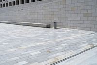 a stone wall sits in the middle of a brick walkway and sidewalk in front of a building with glass windows