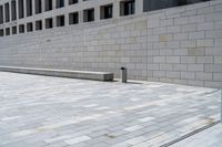 a stone wall sits in the middle of a brick walkway and sidewalk in front of a building with glass windows