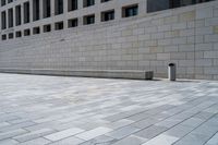 a stone wall sits in the middle of a brick walkway and sidewalk in front of a building with glass windows