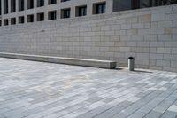 a stone wall sits in the middle of a brick walkway and sidewalk in front of a building with glass windows