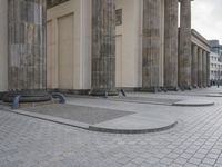 there are steps to put in between a building and another area with large pillars and some benches