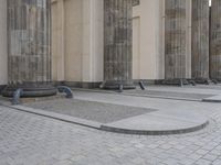 there are steps to put in between a building and another area with large pillars and some benches