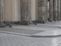 there are steps to put in between a building and another area with large pillars and some benches