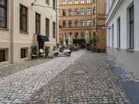 a very small narrow cobble stone street with an old motorcycle parked in the middle