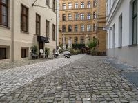 a very small narrow cobble stone street with an old motorcycle parked in the middle