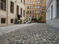 a very small narrow cobble stone street with an old motorcycle parked in the middle