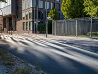 a man riding his skateboard down a long road next to a building with a metal fence