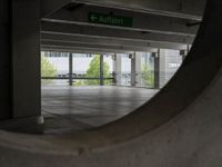 a view through a hole in an indoor parking space, towards a street and building