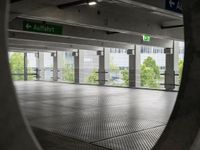 a view through a hole in an indoor parking space, towards a street and building