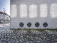 four round air duct vented loues on a stone sidewalk with stone tiles on them