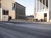 the large, empty sidewalk with multiple columns in front of the building with two signs