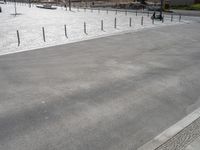 concrete with poles and wires on an empty parking lot outside a building site with cars parked nearby