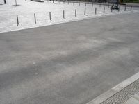 concrete with poles and wires on an empty parking lot outside a building site with cars parked nearby