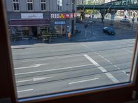 a street view is seen through a window at an intersection with buildings and cars passing by