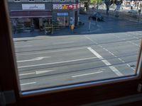 a street view is seen through a window at an intersection with buildings and cars passing by