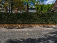 a long empty brick street with tall buildings in the background on a sunny day with some people walking around