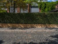 a long empty brick street with tall buildings in the background on a sunny day with some people walking around