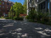 a paved brick street with red trash bins sitting in the middle and trees near to it