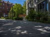 a paved brick street with red trash bins sitting in the middle and trees near to it