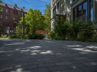 a paved brick street with red trash bins sitting in the middle and trees near to it