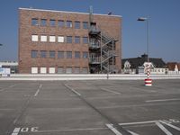 this is an empty parking lot with buildings in the background and a fire escape ladder