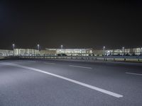 an empty parking lot by some high rise buildings at night, with no cars in the photo