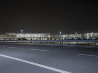 an empty parking lot by some high rise buildings at night, with no cars in the photo