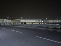 an empty parking lot by some high rise buildings at night, with no cars in the photo