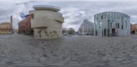 an spherical panorama of a wide open brick road and surrounding buildings with circular designs on it