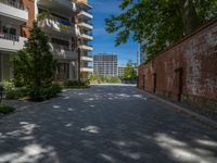 a paved brick street with red trash bins sitting in the middle and trees near to it