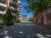 a paved brick street with red trash bins sitting in the middle and trees near to it