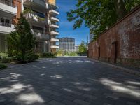 a paved brick street with red trash bins sitting in the middle and trees near to it