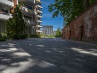 a paved brick street with red trash bins sitting in the middle and trees near to it