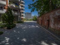 a paved brick street with red trash bins sitting in the middle and trees near to it