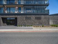 a black brick building with stairs on one side and a glass balcony on the other